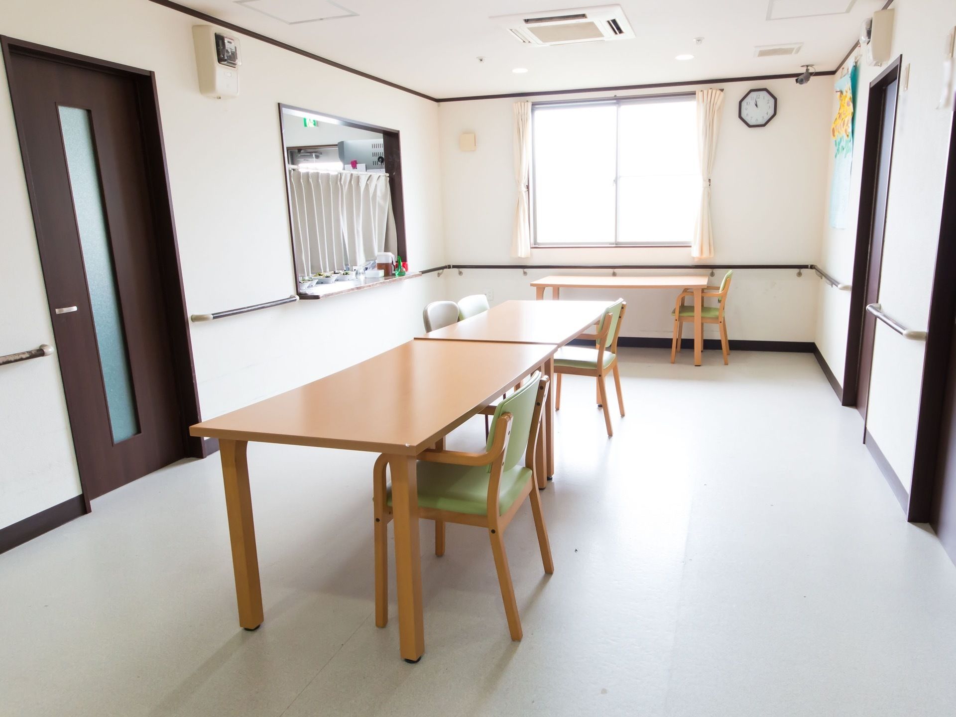 フロアの中央と窓際に、テーブルと椅子が配置されている。カウンターが設置されており、小鉢が並んでいるのが見える。
