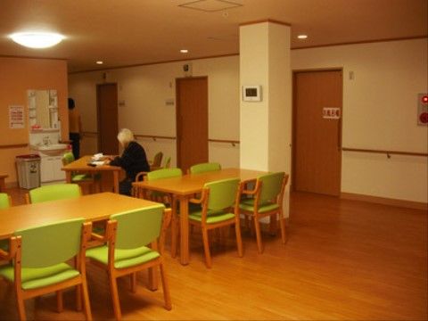食堂には茶色いテーブル、黄緑色の背もたれと座面の椅子が複数、用意されている。洗面台の横にはゴミ箱が置かれている。