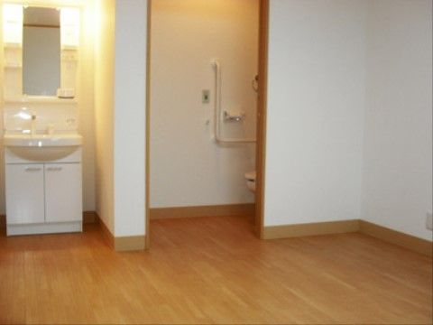 壁で仕切られた洗面台の隣にはトイレがある。トイレの壁側には手すり、呼び出しボタンが設置されており、安全に使用できる。