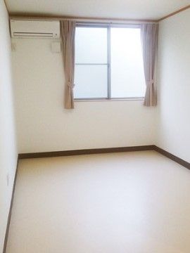 大きな窓の右側が開き、強い光が見えている部屋。窓の横にエアコンが設置されている。きれいに掃除されている。