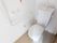 白で統一されたトイレである。非常呼び出しブザーやＬ字型の手すりが完備されている。清掃が行き届いている。