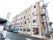 淡いピンクで統一された４階建ての大規模な建物である。周辺に自転車が置かれ、車が横付けされている。非常階段が完備されている。