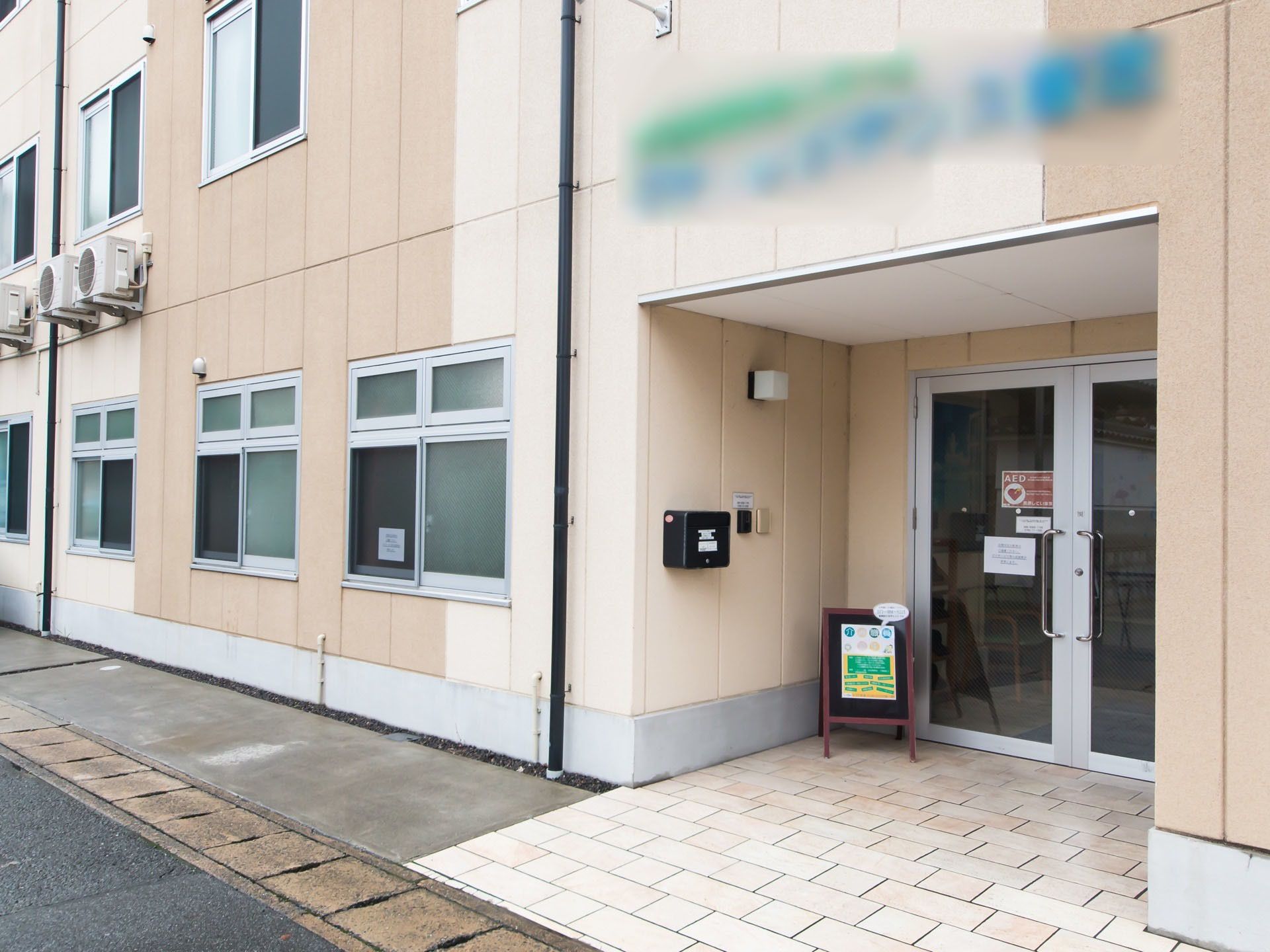 濃淡のベージュのコントラストが美しい建物である。エントランスの奥の玄関入口は、両開きのガラスドアである。