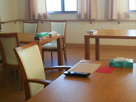 テーブルと白い椅子が並んだリビングの壁には手すりが備え付けられている。車椅子に座ったまま食事をとることができる。