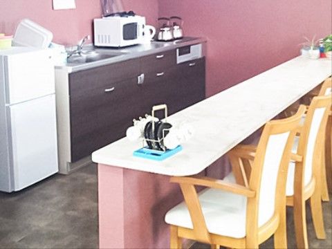 カウンターのあるキッチンで入居者様の食事を作っている。木目調のIHコンロのキッチンには、小型冷蔵庫やレンジが置かれている。