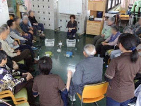 リビングルームでリクリエーションを車座になって楽しむ入居者