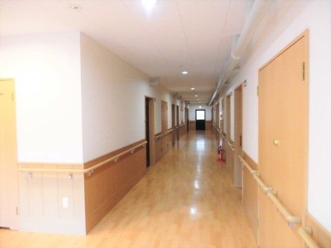 廊下には、淡い茶色のフローリング・ドア・手すりなどが並んでいる。柔らかい色合いで、ゆっくりと歩いて行くのにぴったりな温和な雰囲気である。