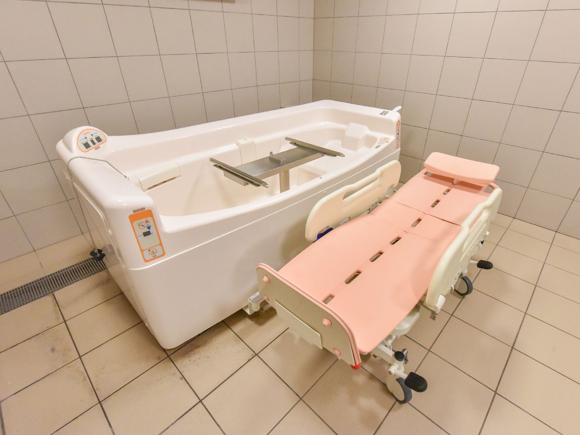 座ったままでも入ることができる介助バスが用意してあるので、四肢に問題がある人でもお風呂が楽しめる。壁と床がタイルの風呂場である。