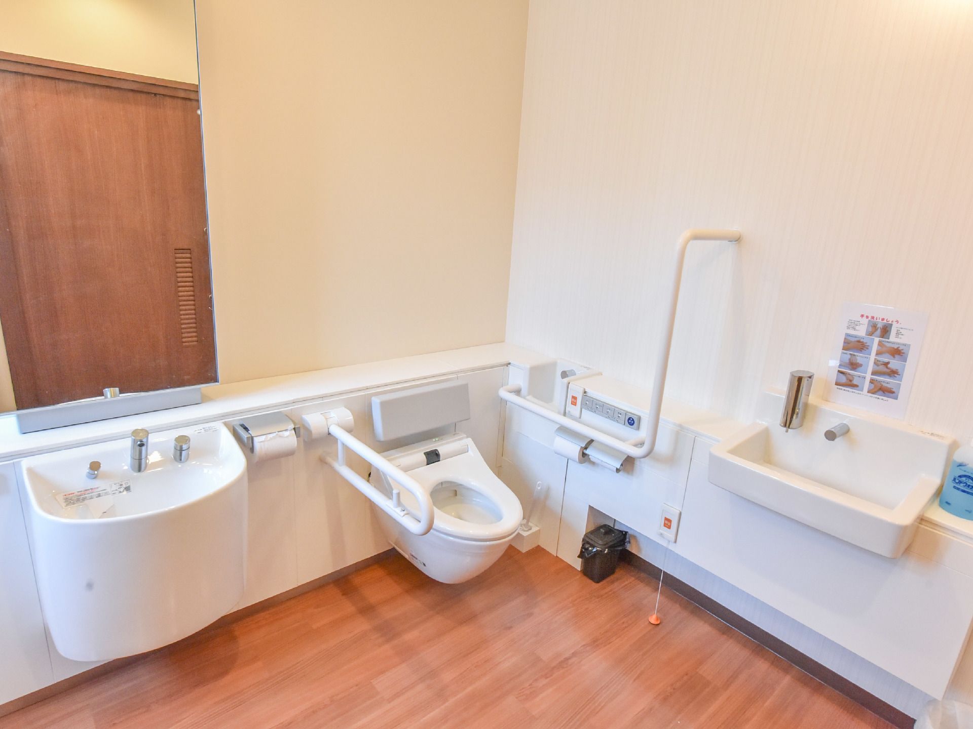 白い洗面台が付いたトイレで、レバー式の蛇口なので力を入れずに吐水量を変えることができる。大面鏡が設置してある。