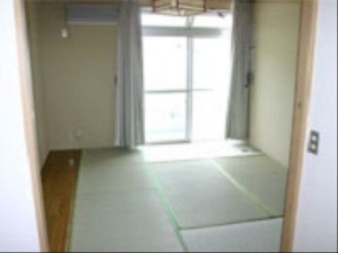 居室は、畳式の和室である。窓やエアコンが完備され、窓から日差しが入り、カーテンが両側に寄せられている。