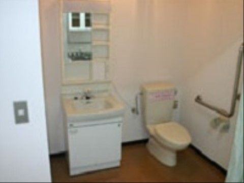 Ｌ字型手すりが設置されたトイレの横には、収納付き洗面化粧台が設置されている。スペースは広く確保されている。