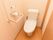 白い壁とライトブラウンを基調とした個室のトイレがある。壁には手すりが設置され、呼び出しブザーと温水洗浄便座が付いている。