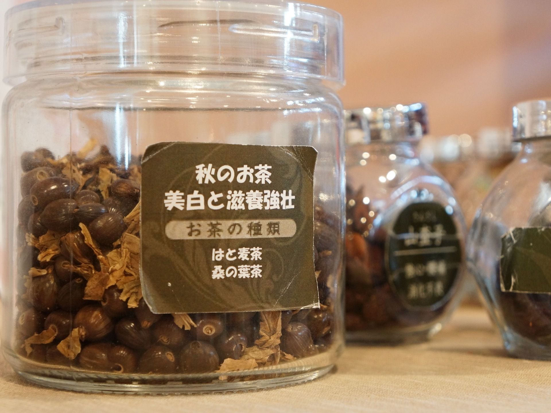 ガラス瓶がいくつか並んでいる。ガラス瓶の中には、自然の材料を使った様々な種類のお茶が入れられている。