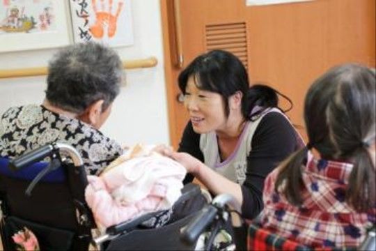 車椅子に乗った入居者に微笑みながら手を添える介護スタッフ