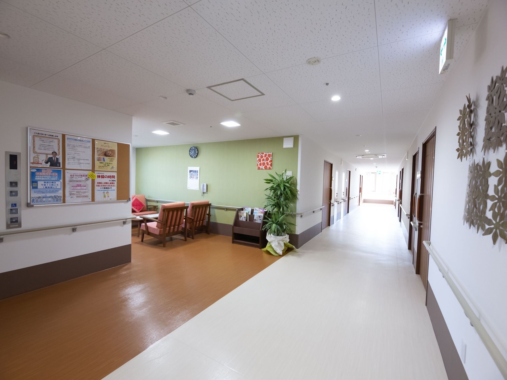 白色を基調とした通路はとても明るい。脇には休憩スペースが設けられている。また、壁には掲示板が設置されている。