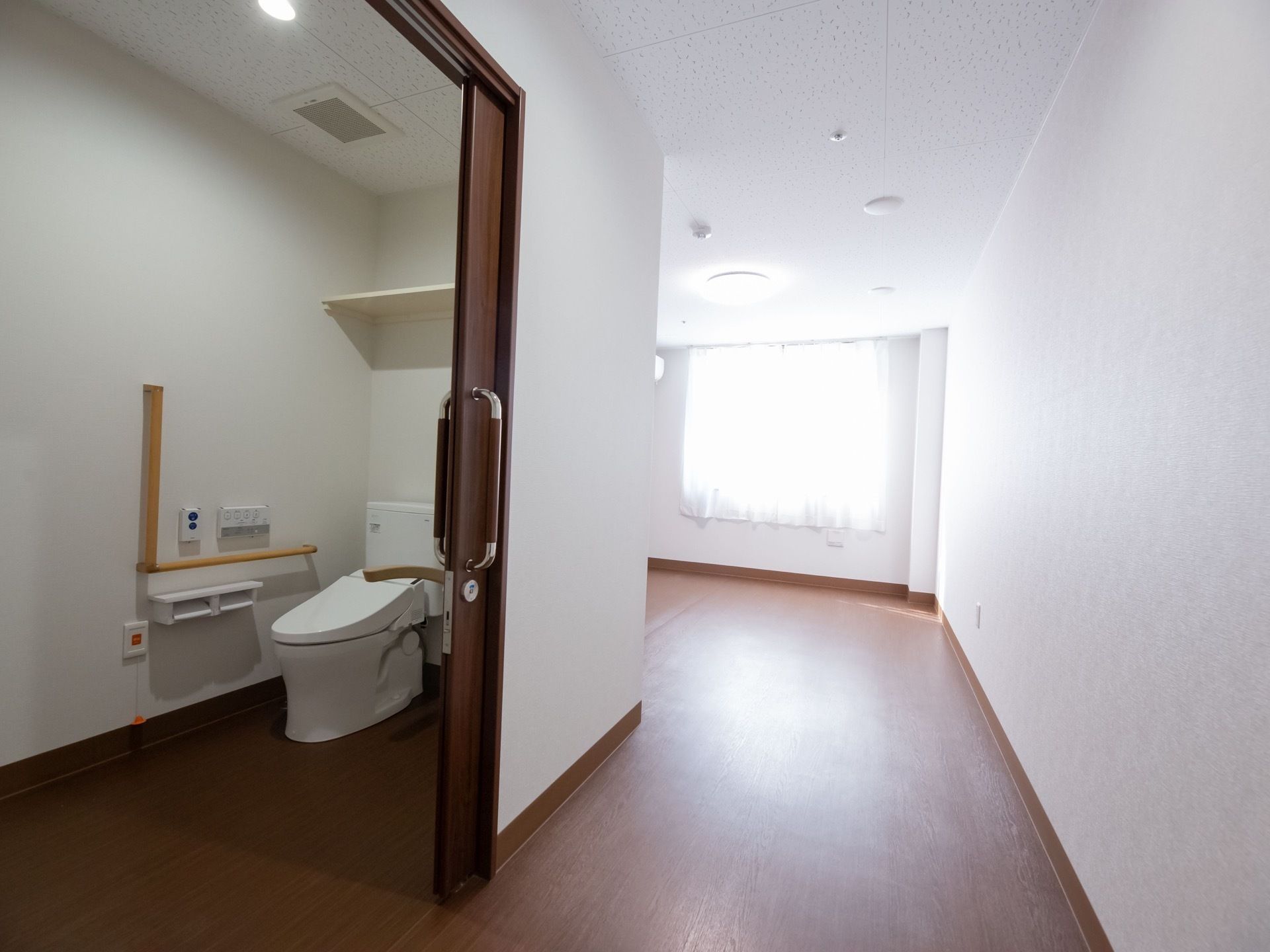 居室に設置されているトイレである。ドアは引き戸で段差がなく出入りしやすくなっている。温水洗浄便座仕様で清潔である。