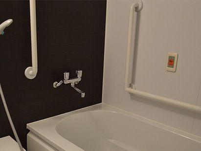白いユニットバスが完備された浴室の壁には、呼び出しブザーや手すりが設置されており、安全な立ち座りができ急な体調変化にも安心できる。
