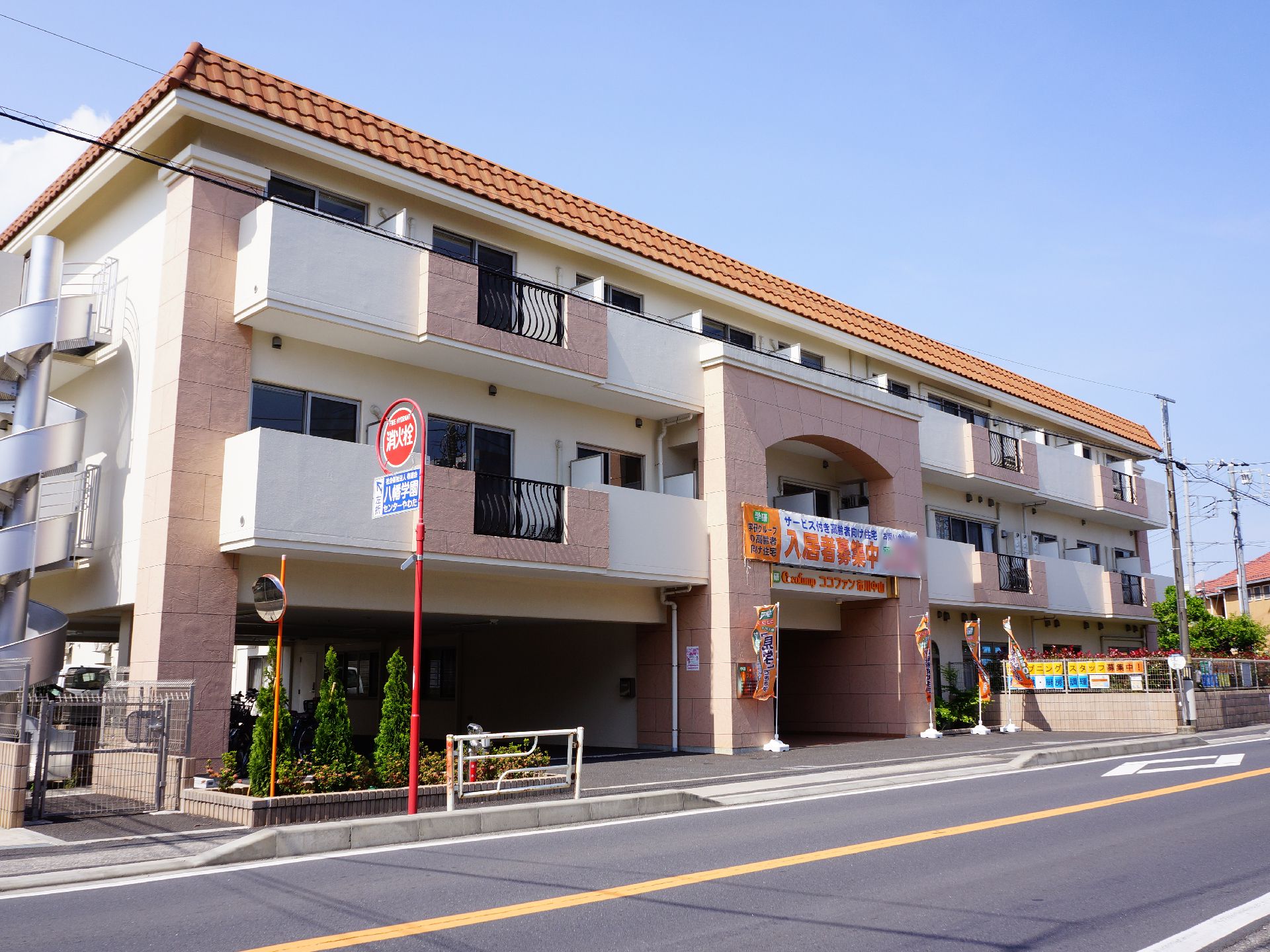 １階部分が駐車場になったピンク色の壁が可愛らしい雰囲気の３階建ての施設