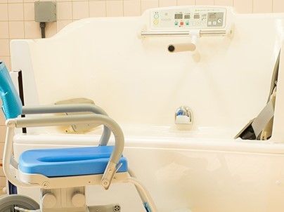 真っ白な介護浴槽の横には、介護入浴用の椅子が設置されている。浴槽への出入りがスムーズに行えるため、快適に入浴を行うことができる。