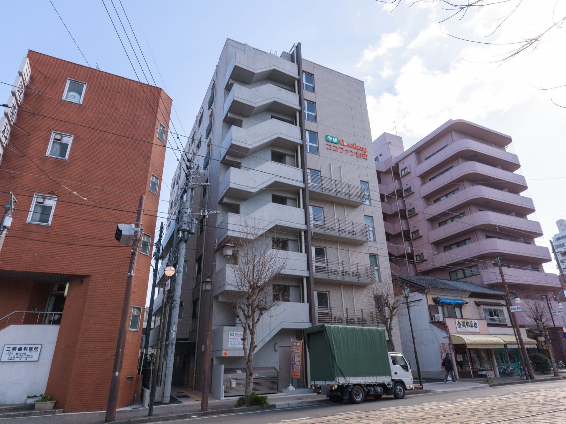 ８階建てのマンションタイプの外観である。正面左側には非常階段があり、右側の上部の壁に施設の名称が設置されている。