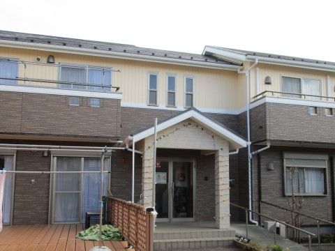 ツートーンの2階建て長屋で、1階の1部分はウッドデッキ