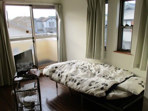 居室はワンルームタイプの洋室である。床面はダークブラウンのフローリングで段差がない。掃き出し窓と出窓のような小さめの窓が付いている。
