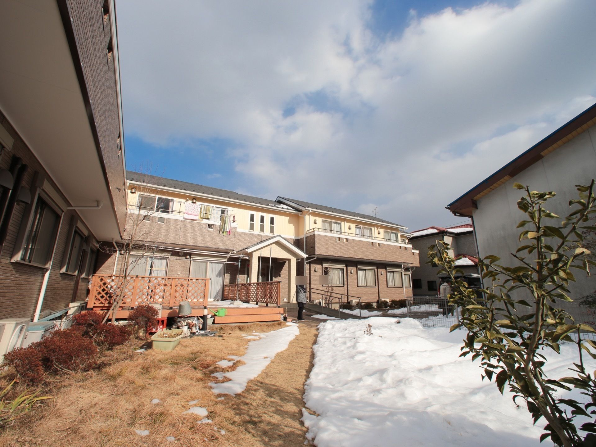 施設の建物の前面は広々とした庭で、日差しを遮るものは何もない。玄関前には手すり付きのスロープを設置している。