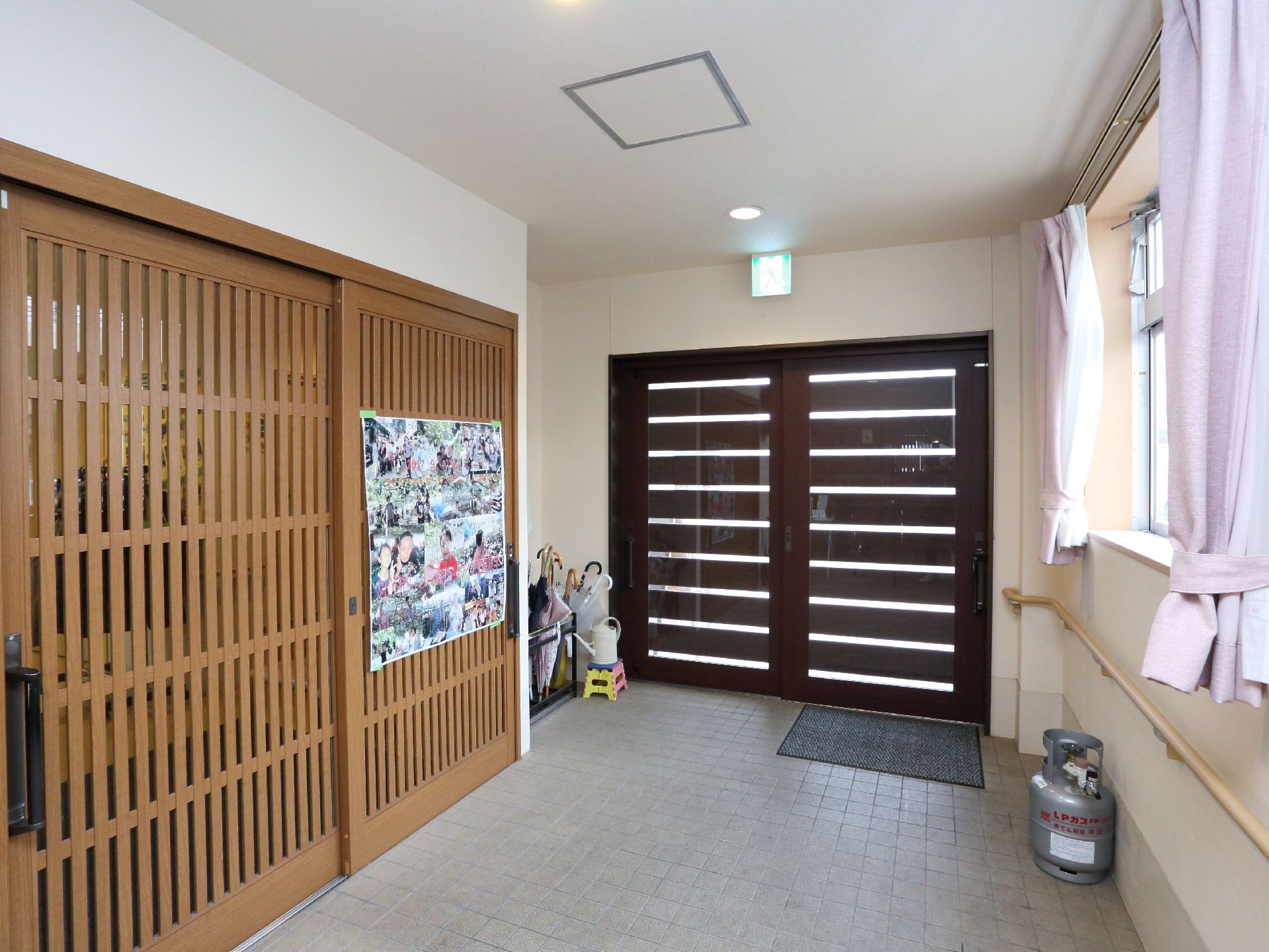 広さのあるエントランス。外からの入り口と館内への入り口にはスライド式のドアがつけられている。施設での様子がわかる写真が掲示されている。