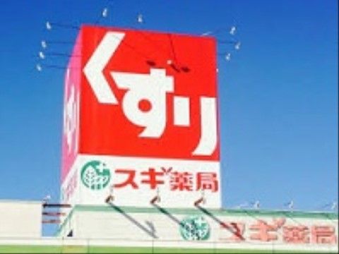 建物上に設置されている照明の付いた赤いドラッグストアの看板である。外壁上部にも施設名が大きく書かれている。