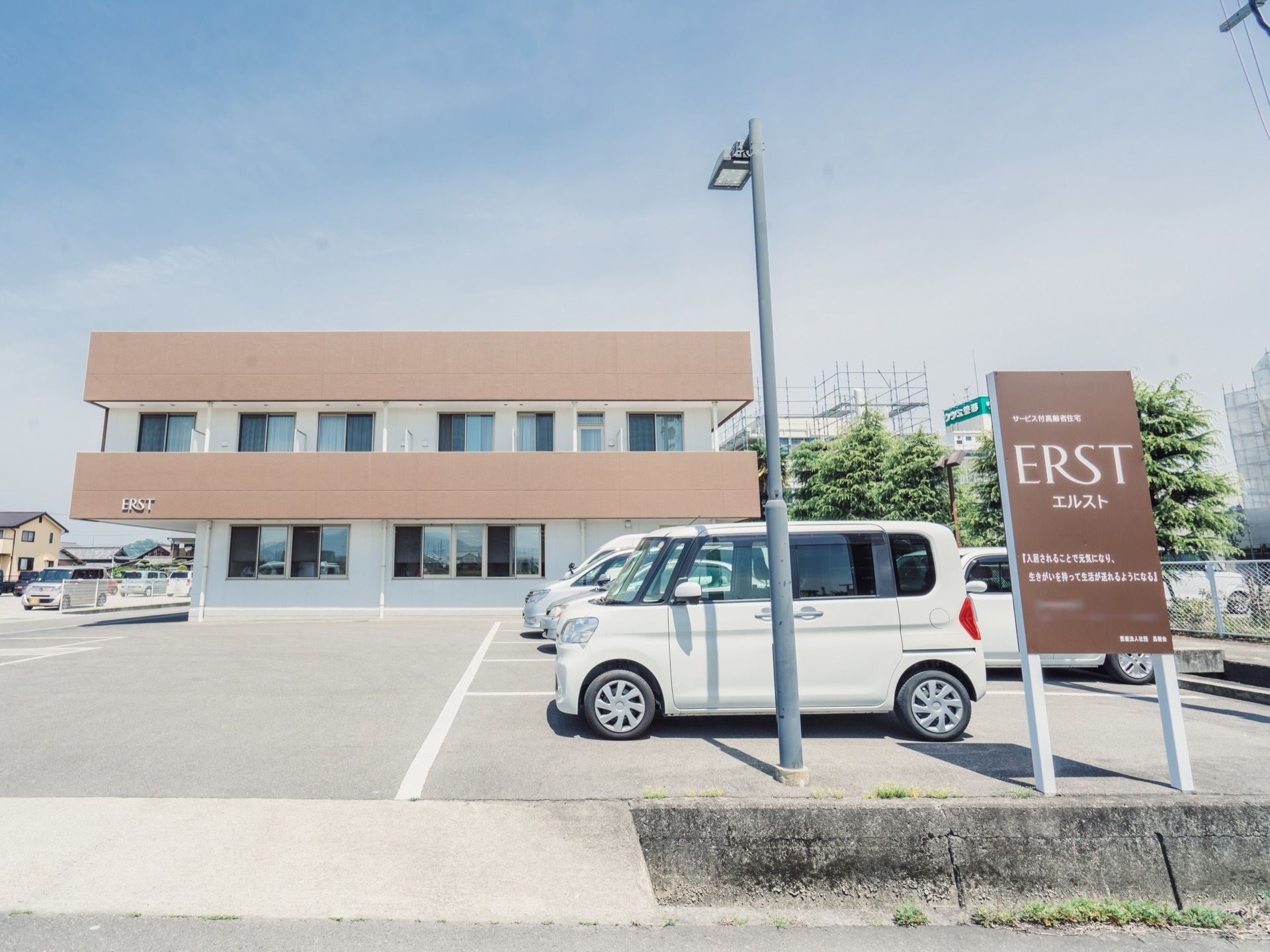 道路面から少し高くなっている敷地に建つ施設である。道路からの導入路の右横に、縦長の看板が設置されている。