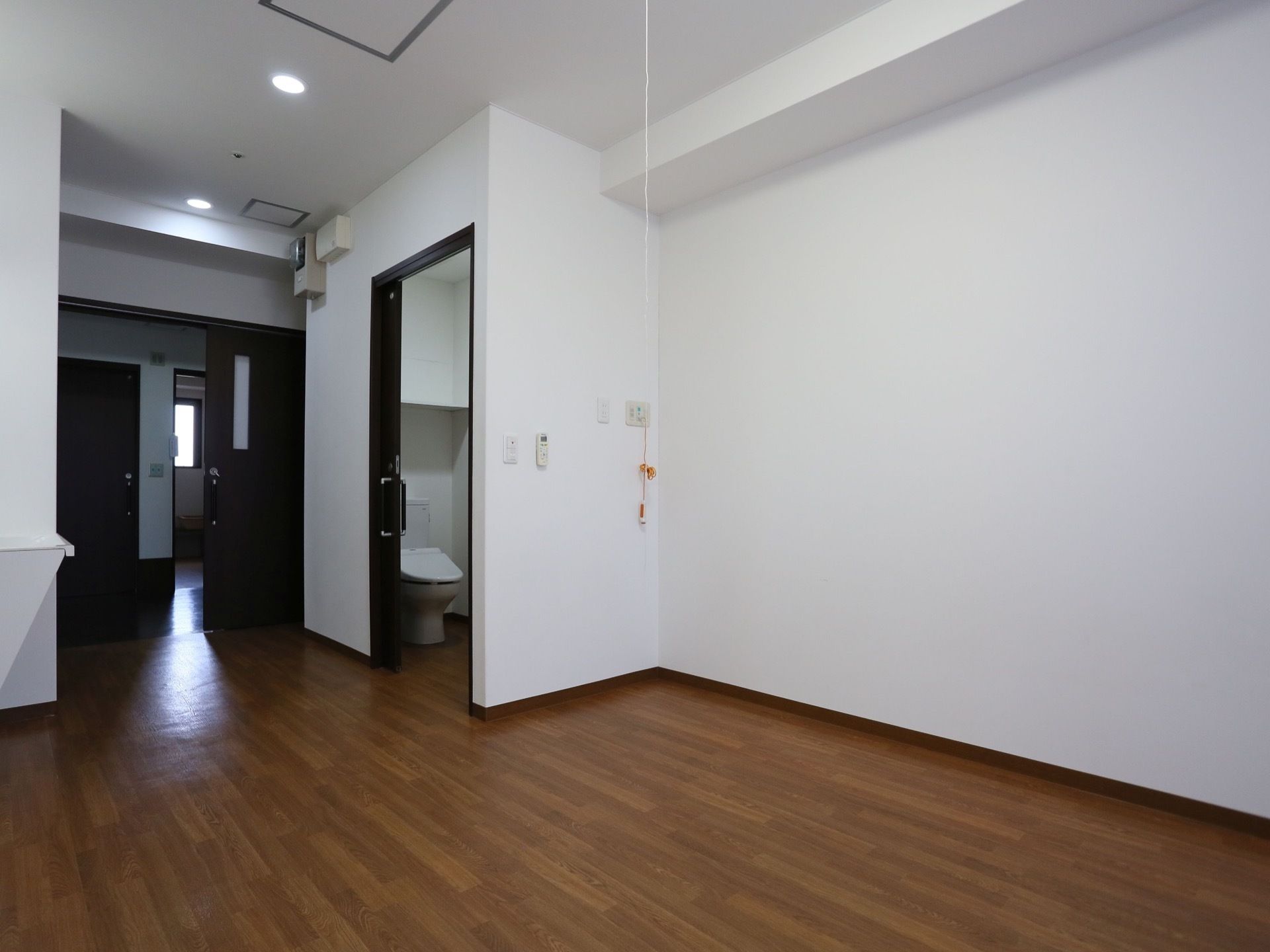 居室は、入居者様が生活のしやすい充分な広さが確保されている。入口とトイレには、黒い引戸が取りつけられている。