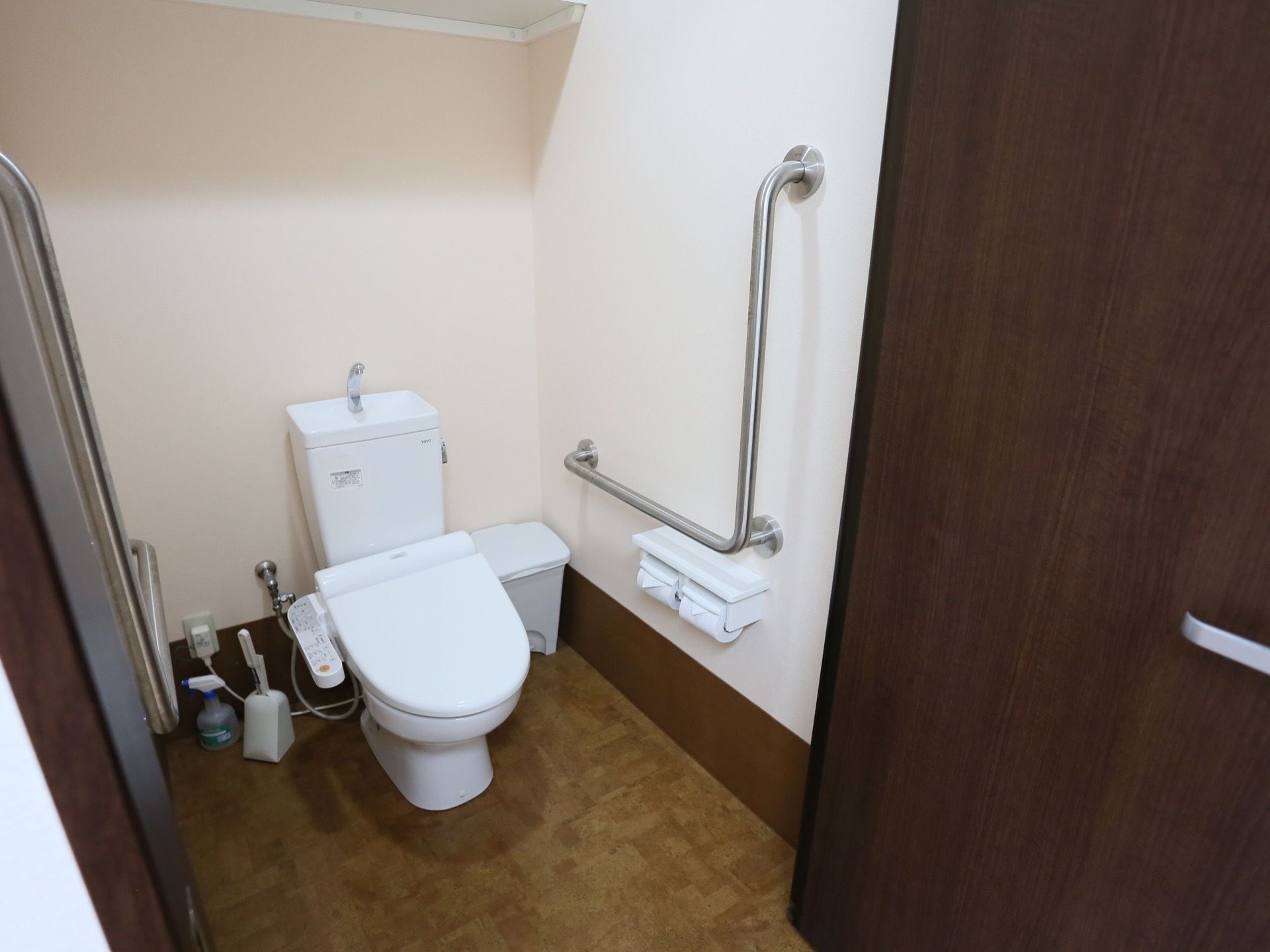 トイレは充分な広さが設けられており、両サイドの壁には手すりが取りつけられている。部屋の隅には、ゴミ箱が置かれている。