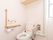 広いスペースにトイレがある。便座脇に手すりとひじ掛けが設置されている。トイレットペーパーホルダーが２つある。