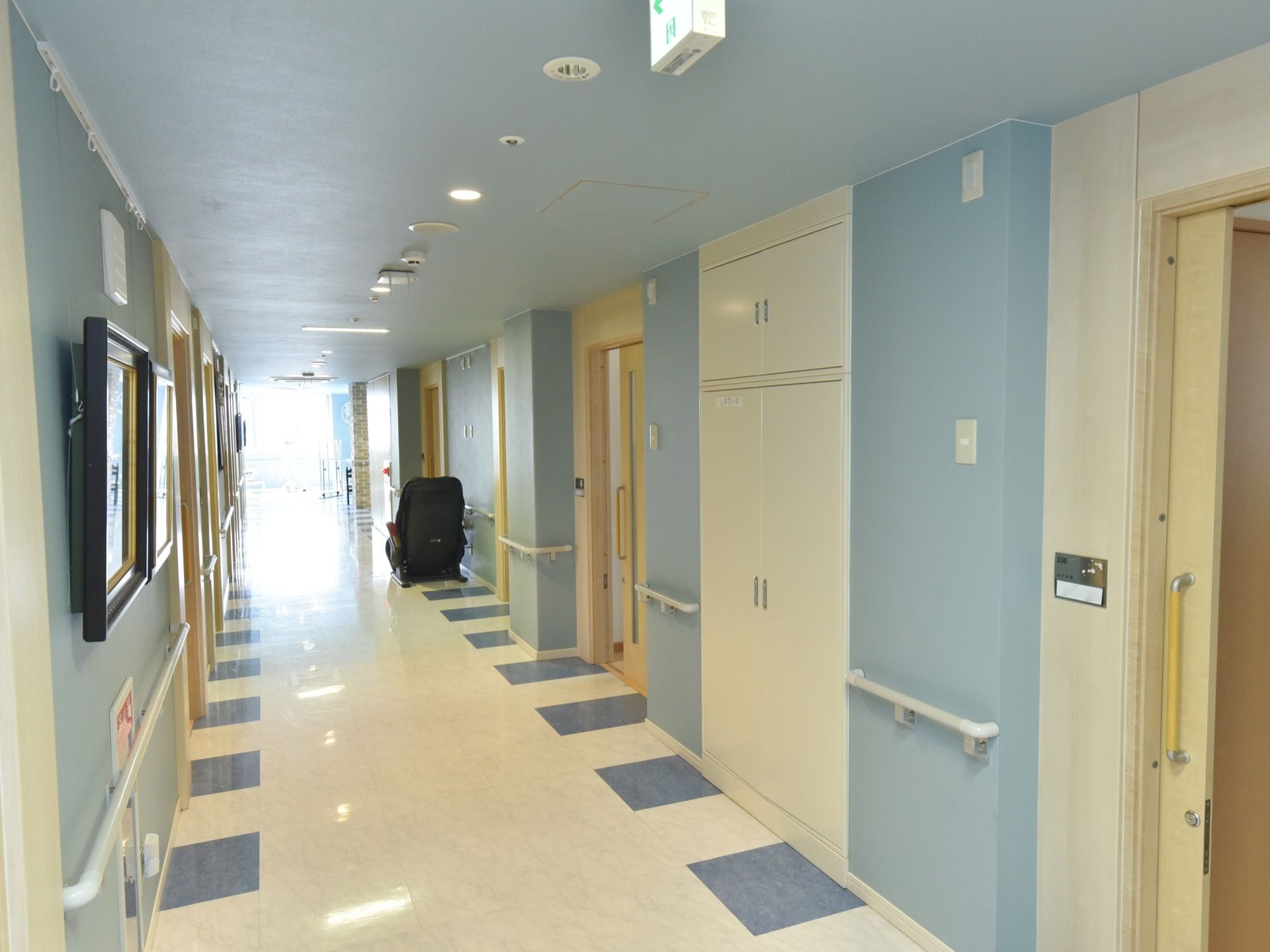 廊下には水色の壁紙が貼られており、各居室の扉は薄い黄色となっている。奥からは外からの明るい光が降り注いでいる。