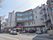 建物の前に自動販売機が数台置かれており、桜の木が植えられている。玄関はガラス張りの自動ドアで、上に屋根がついている。