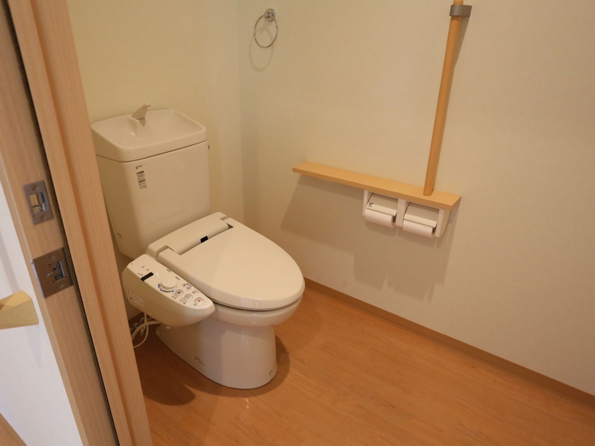 清潔感のある広いスペースを確保したトイレである。手すりを設置しており、立ち上がる際に体を支えることができる。