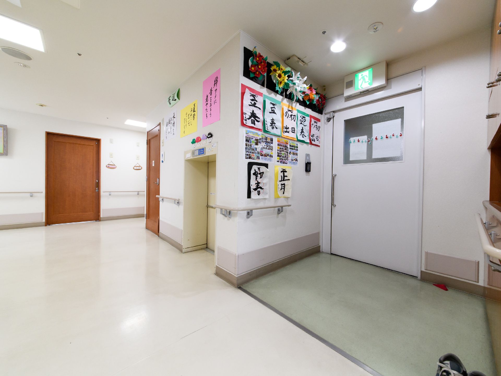居室がある廊下前で、壁には手すりがついているので、掴まりながら移動ができる。壁に入居者様が書いた書道作品が飾ってある。