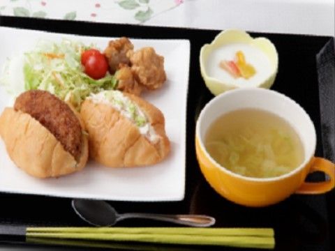 カツやサラダが挟まれたパンや大きなから揚げ、スープなどお箸で細かい動きをしなくても食べられるような工夫のされた食事である。