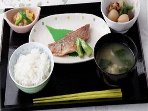 主菜は焼き魚、汁物に味噌汁と副菜が２つ付いた和風の食事。栄養のバランスと共にインゲンやコーンなどで彩りもあり食事を楽しめる工夫がされている