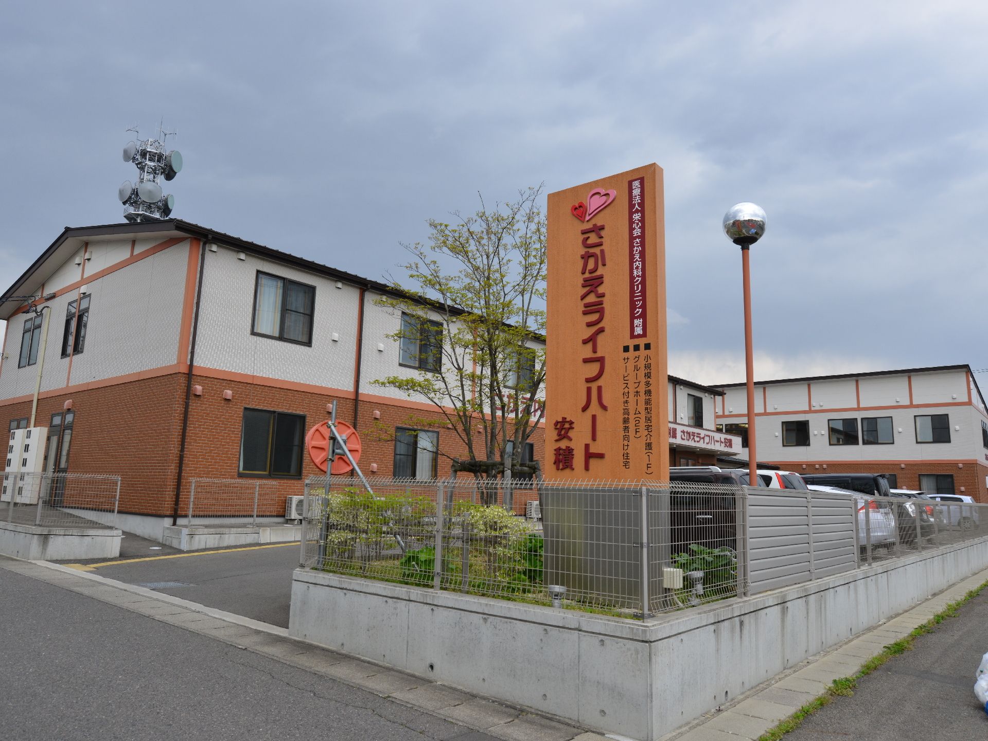 二階建ての施設の外観である。表には大きな看板が置いてある。駐車場が完備されており、駐車場出入り口には段差はない。