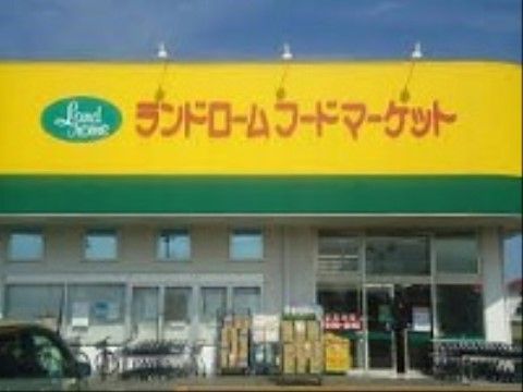 スーパーマーケットの外観である。黄色の屋根には店舗名が表示されている。入口の横には自転車が置かれている。