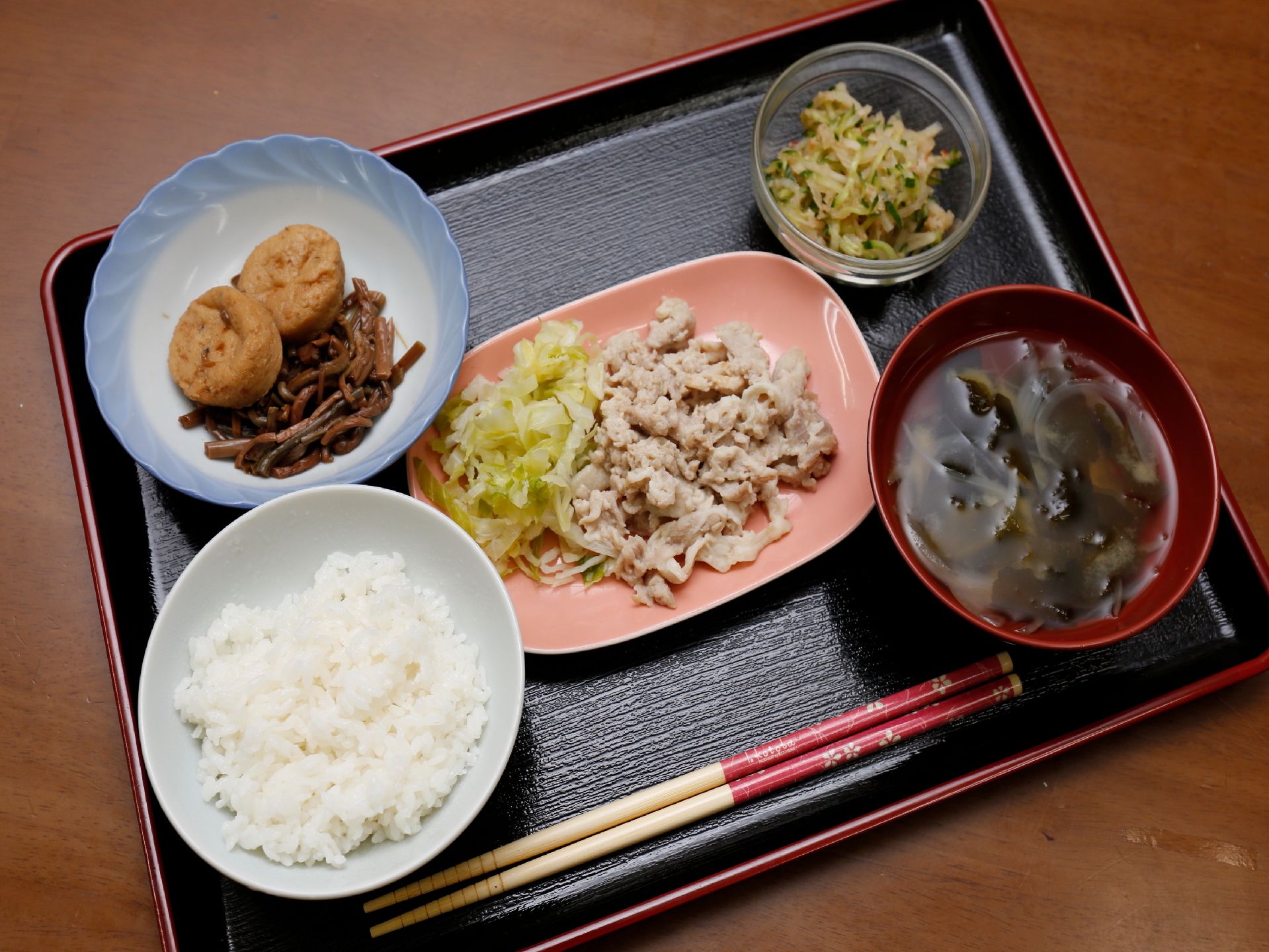 黒塗りのお盆の上にご飯や汁物、おかずののった3つのお皿が並んでいる。様々な食材を使ったメニューは彩りも豊か。