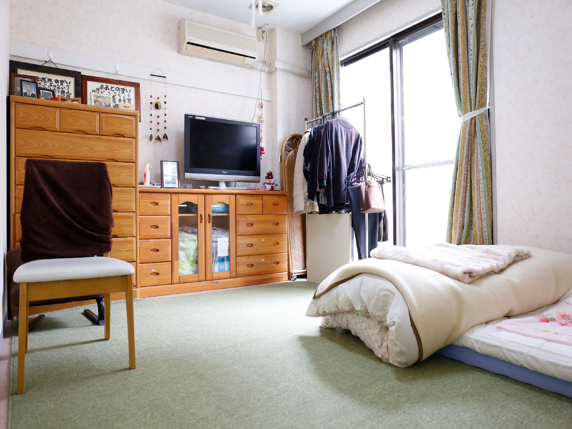 タンスやテレビ、洋服掛け等がある、ご自宅に居るようなカーペット敷きの居室
