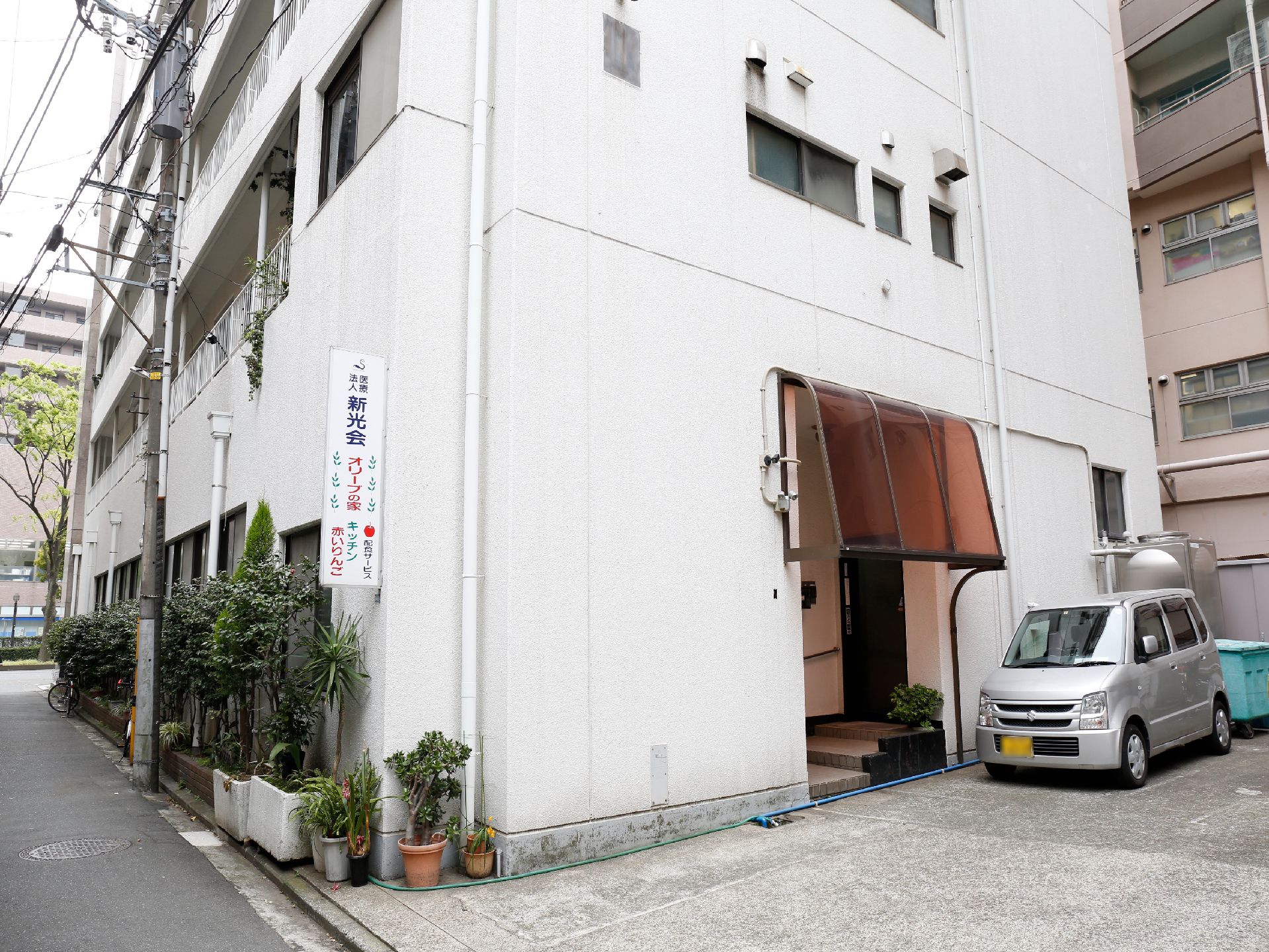 白い外観に雨よけの庇、３段の階段と手すりの付いたエントランス