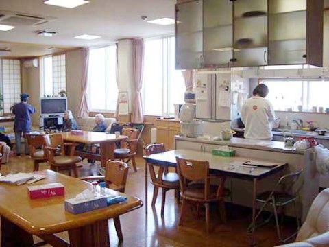 日の差す、オープンキッチンのあるリビングで寛ぐご入居者様