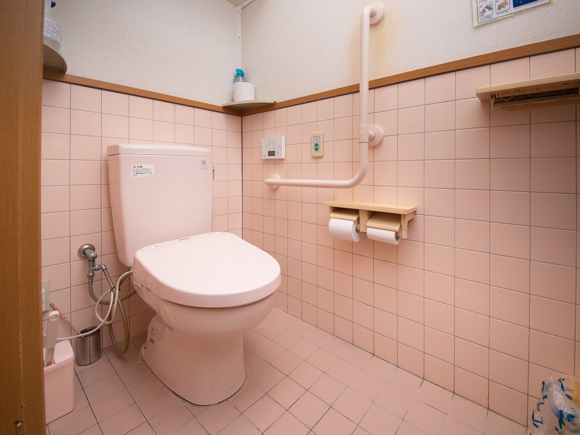 白を基調としたトイレで、壁にはＬ字型の手すりやナースコールが設置されている。床はタイル張りとなっている。