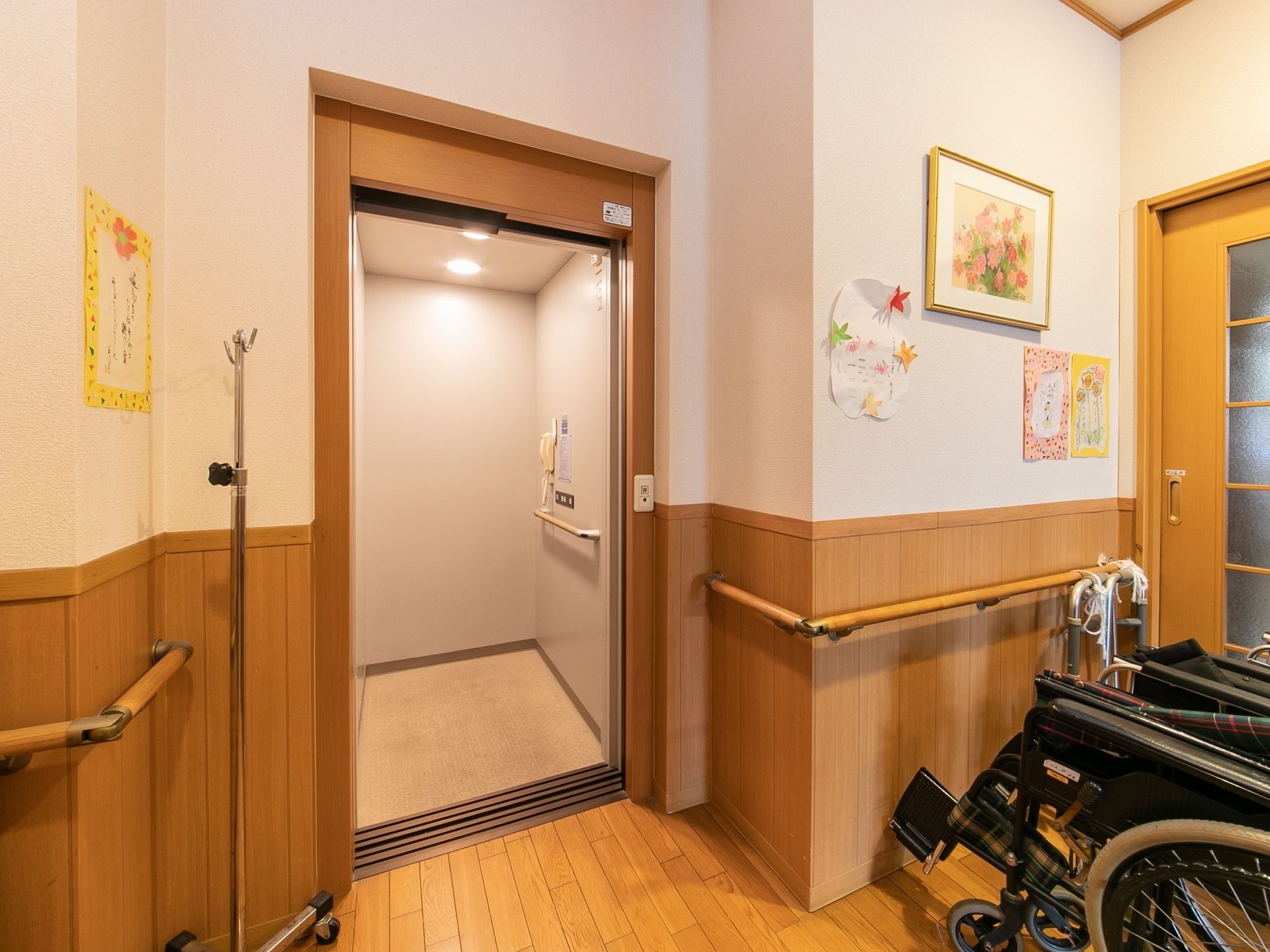 ホーム内のエレベーターは、周りの内装に馴染む、茶色いドア枠になっている。内部には、電話機と手すりがついている。