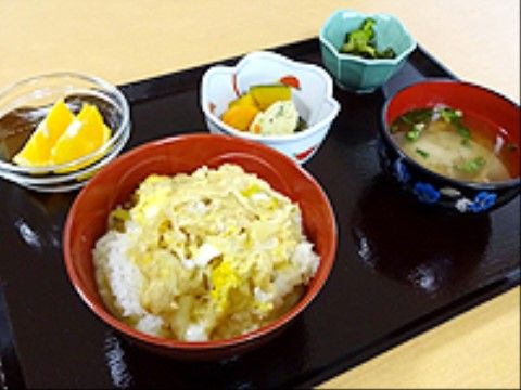 親子丼と味噌汁、煮物や酢の物、フルーツを乗せたお盆