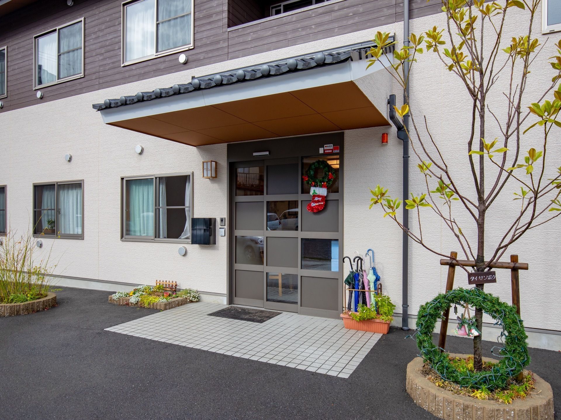 玄関は段差をなくし、どなたでも出入りがしやすいバリアフリーである。外回りには木や植物が植えられ、季節の飾りつけもされて明るい雰囲気である。