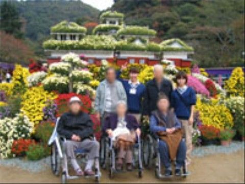 外出イベントで、花のある公園を楽しまれるご入居者様と職員